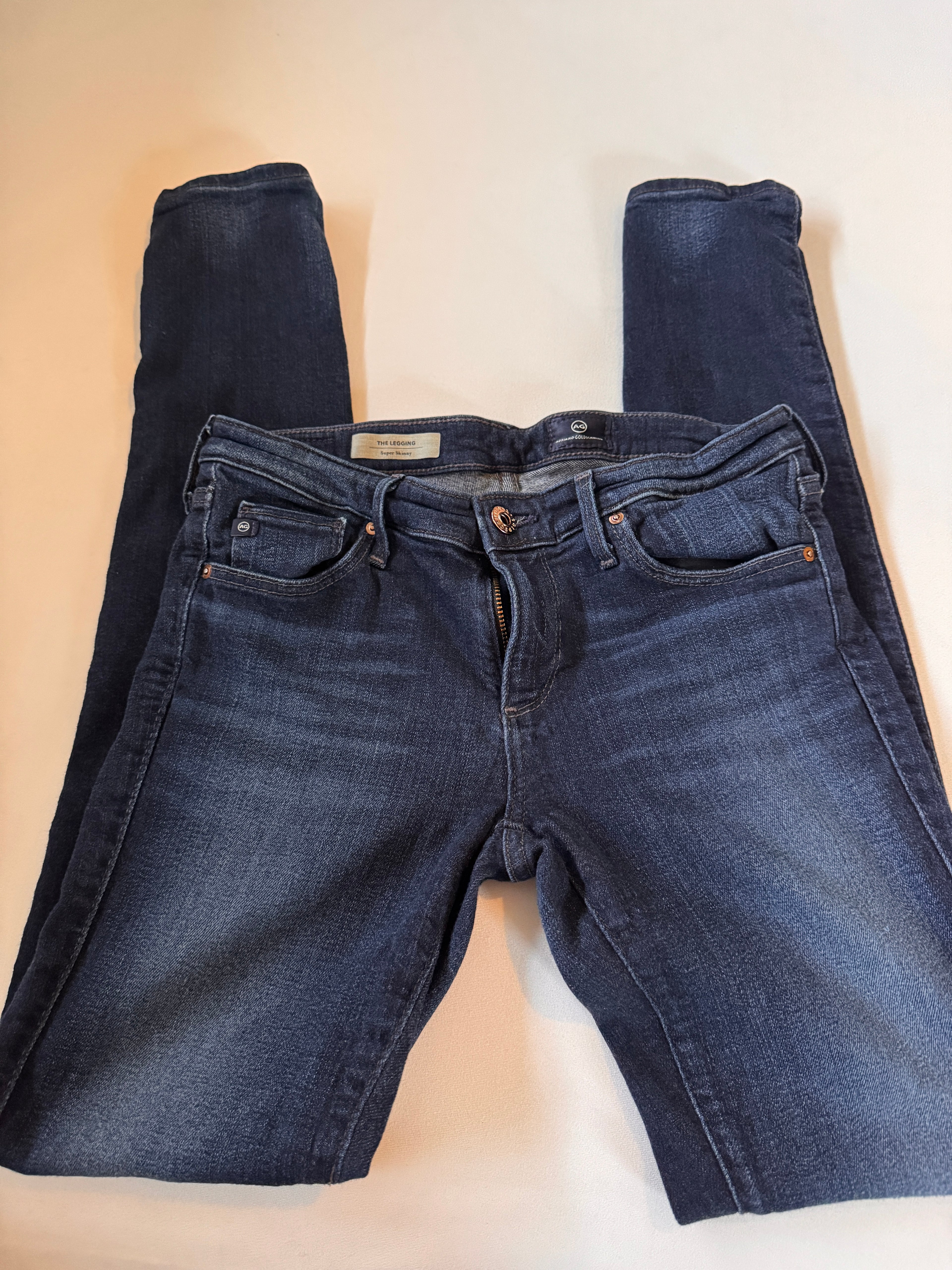 Folded pair of blue jeans on a beige surface