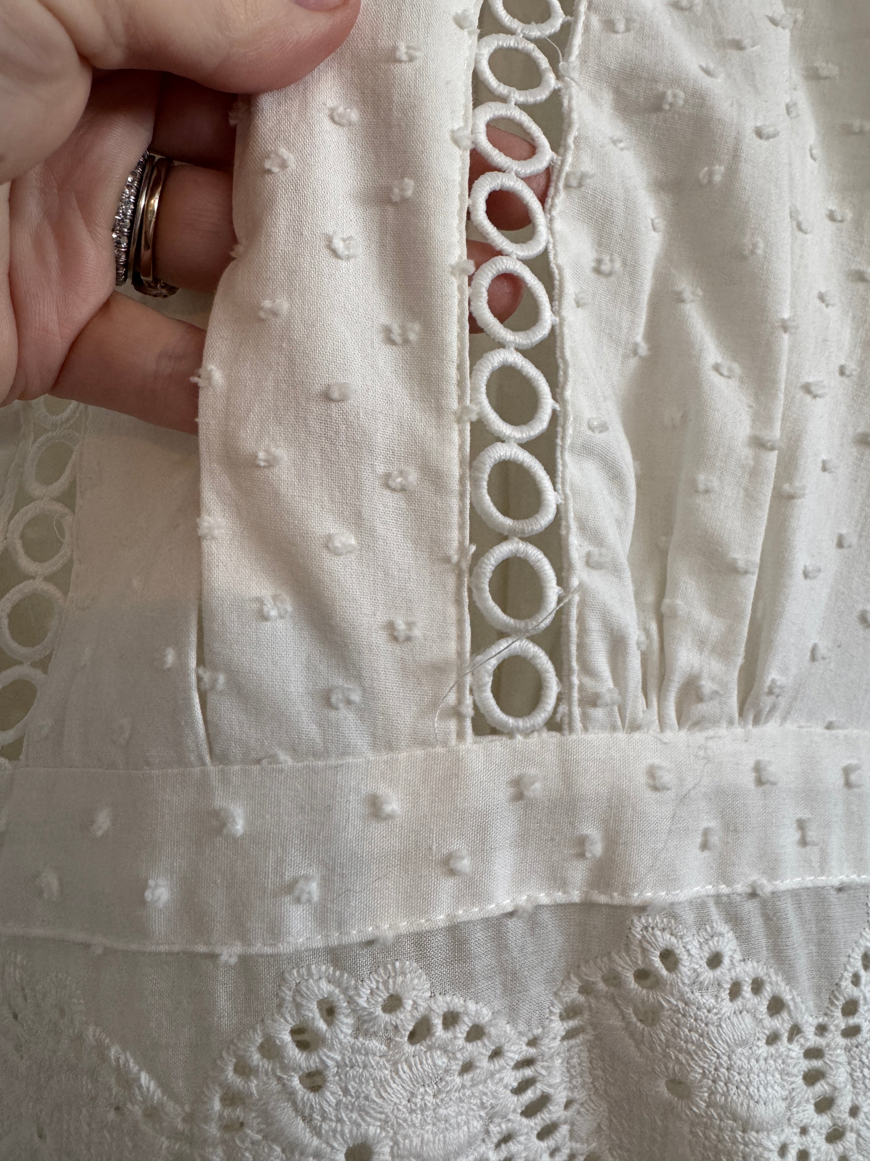 Close-up of white embroidered fabric with a hand holding it