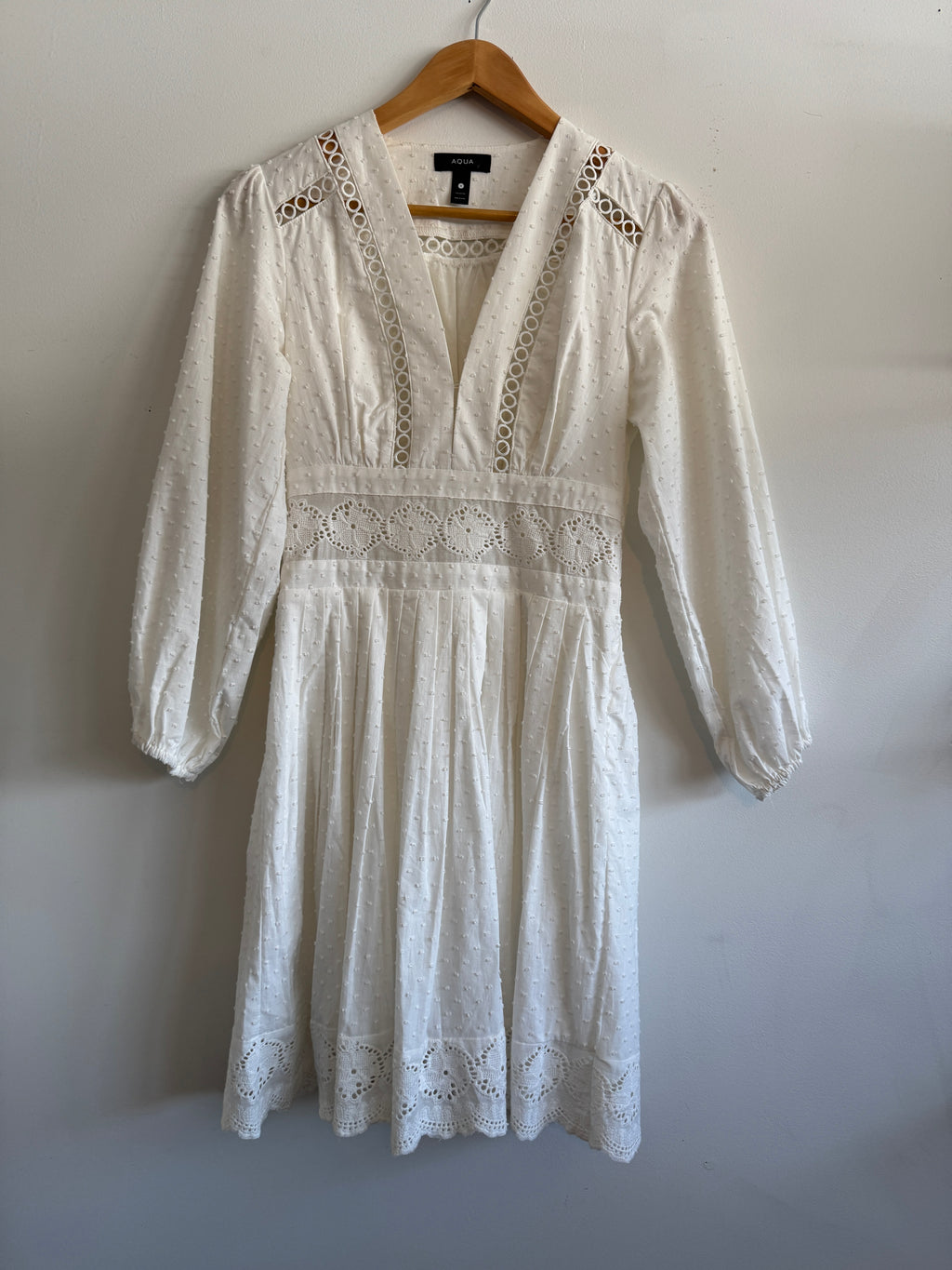 White lace dress on a wooden hanger against a white background