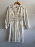 White lace dress on a wooden hanger against a white background