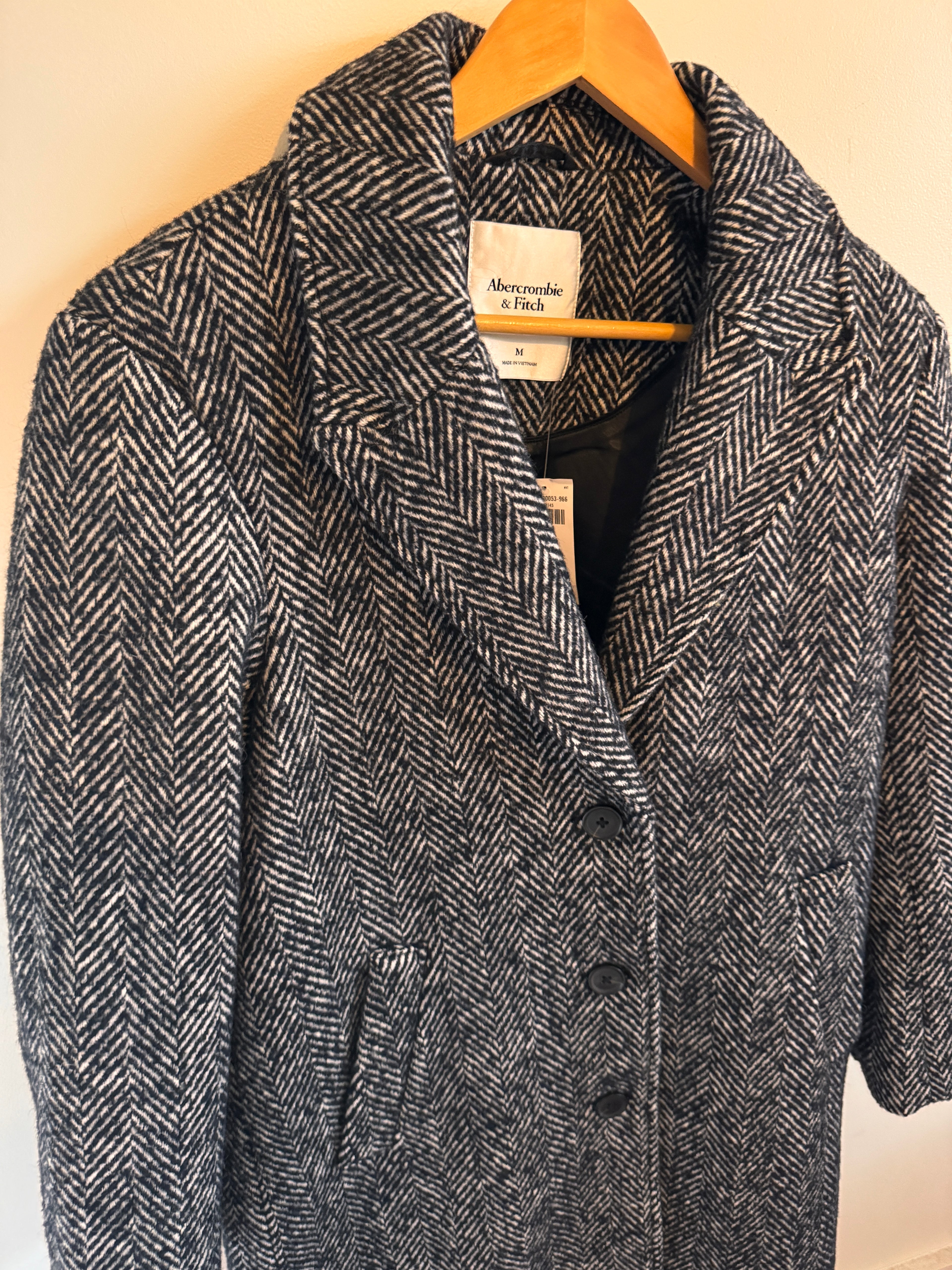 Folded gray herringbone fabric with a visible brand label on a beige surface