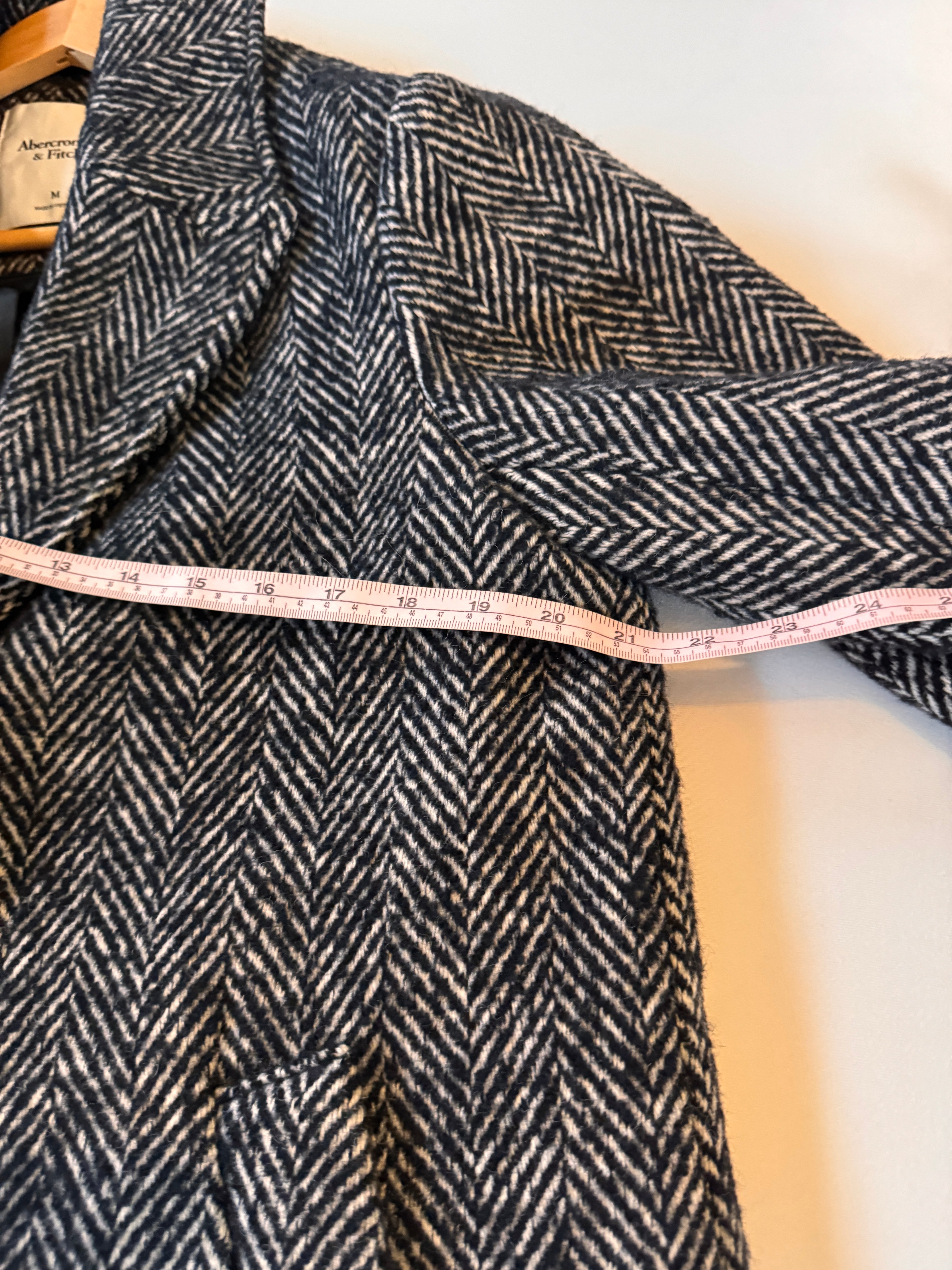 Herringbone fabric with a measuring tape draped over it on a light background