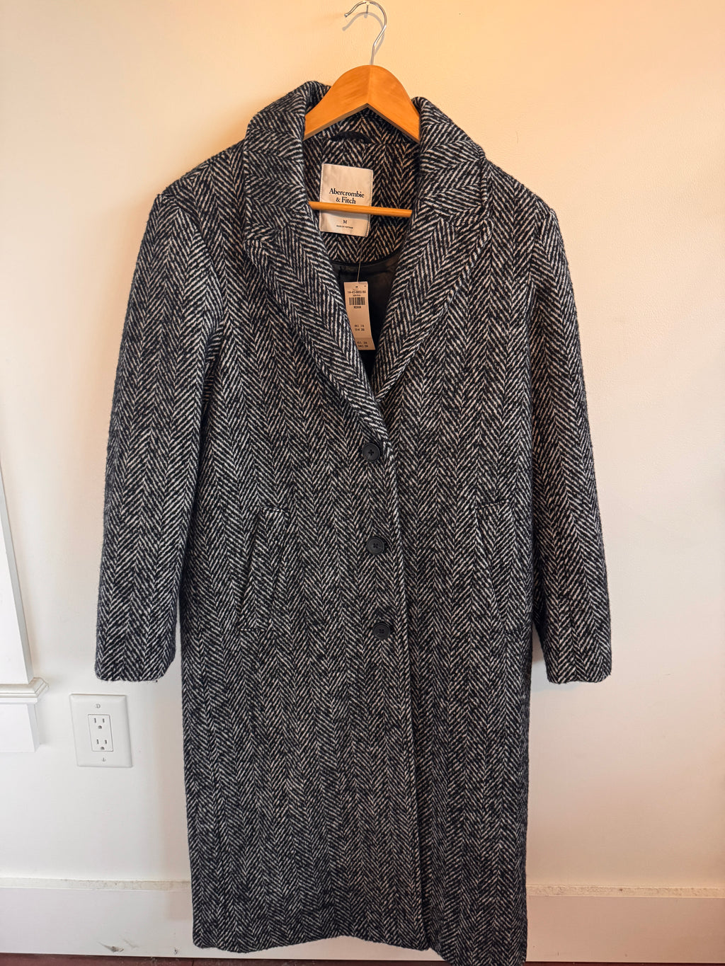 Gray textured jacket on a hanger against a neutral background