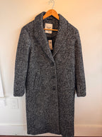 Gray textured jacket on a hanger against a neutral background