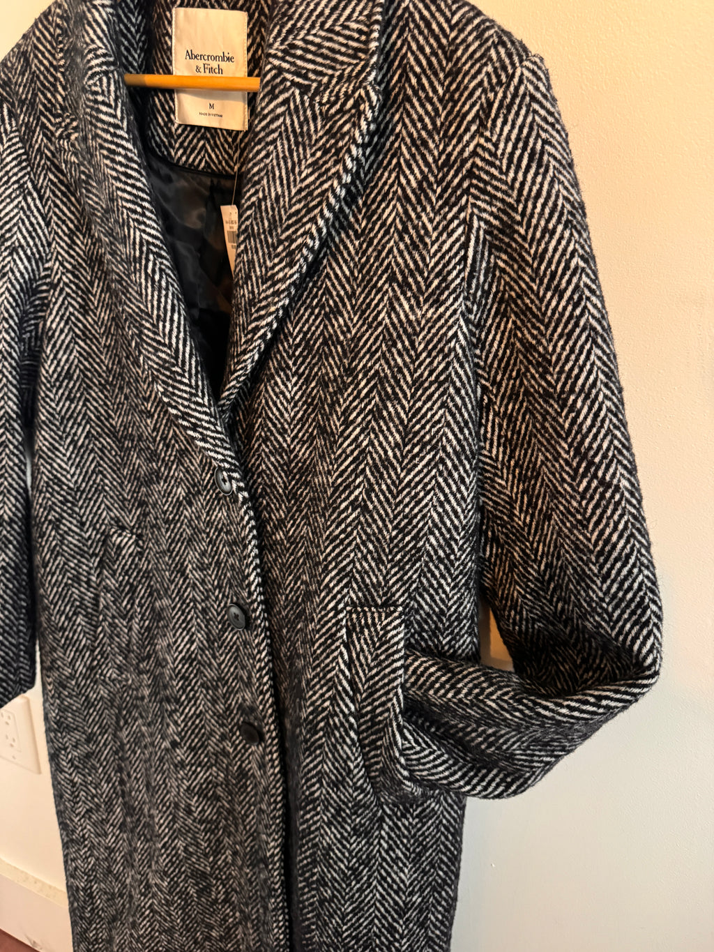 Gray herringbone fabric with a visible brand tag on a beige background