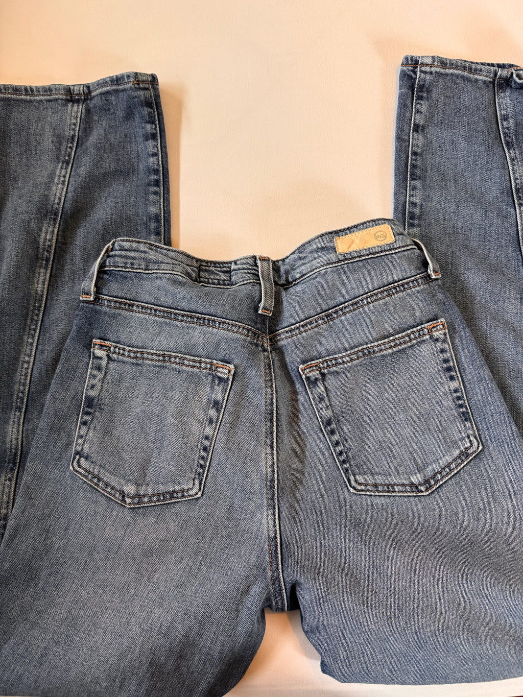 Pair of blue jeans laid flat on a beige surface