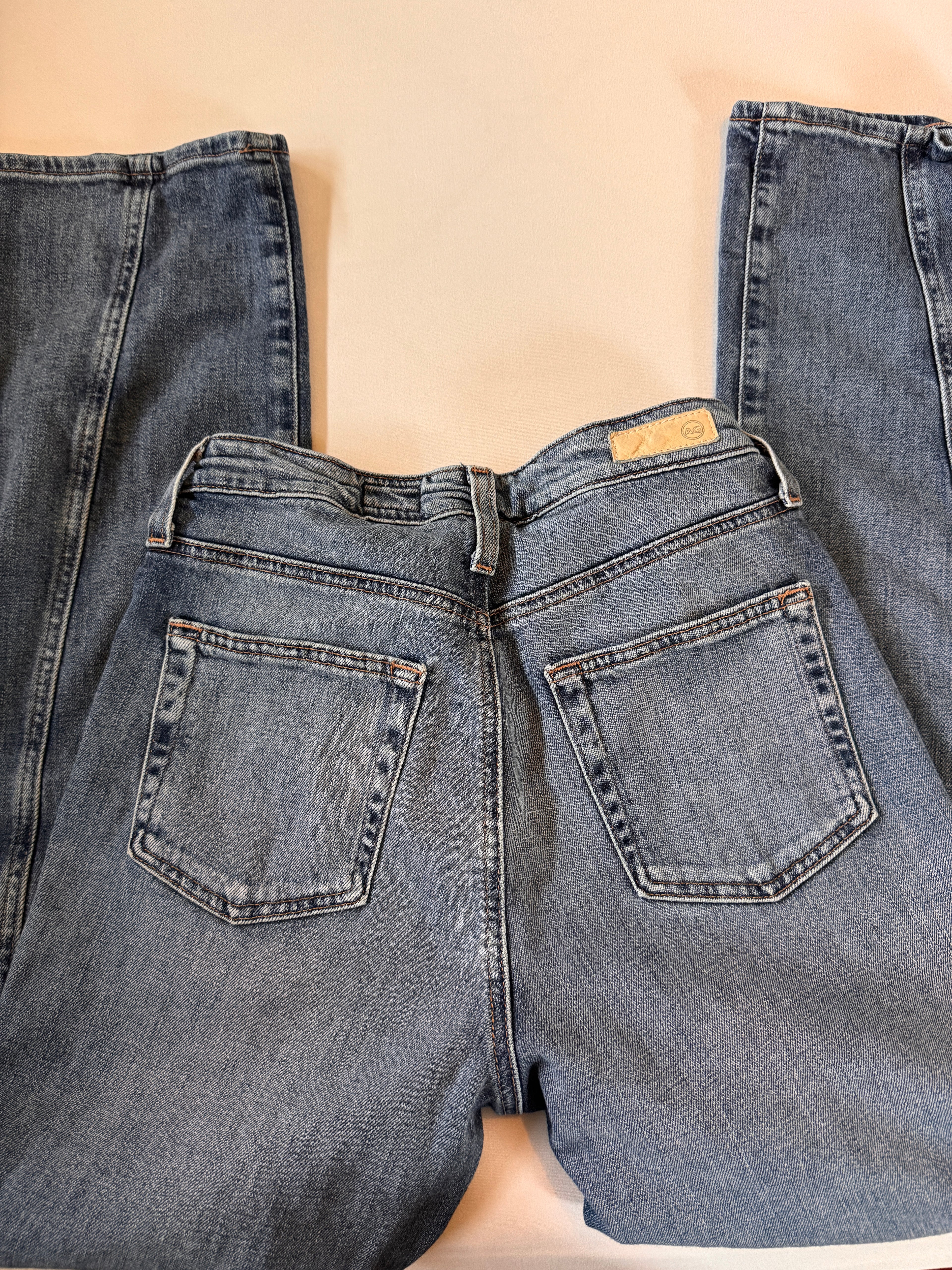 Pair of blue jeans laid flat on a beige surface