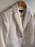 White textured jacket on a hanger against a light background