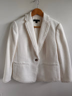 White textured jacket on a wooden hanger against a white background