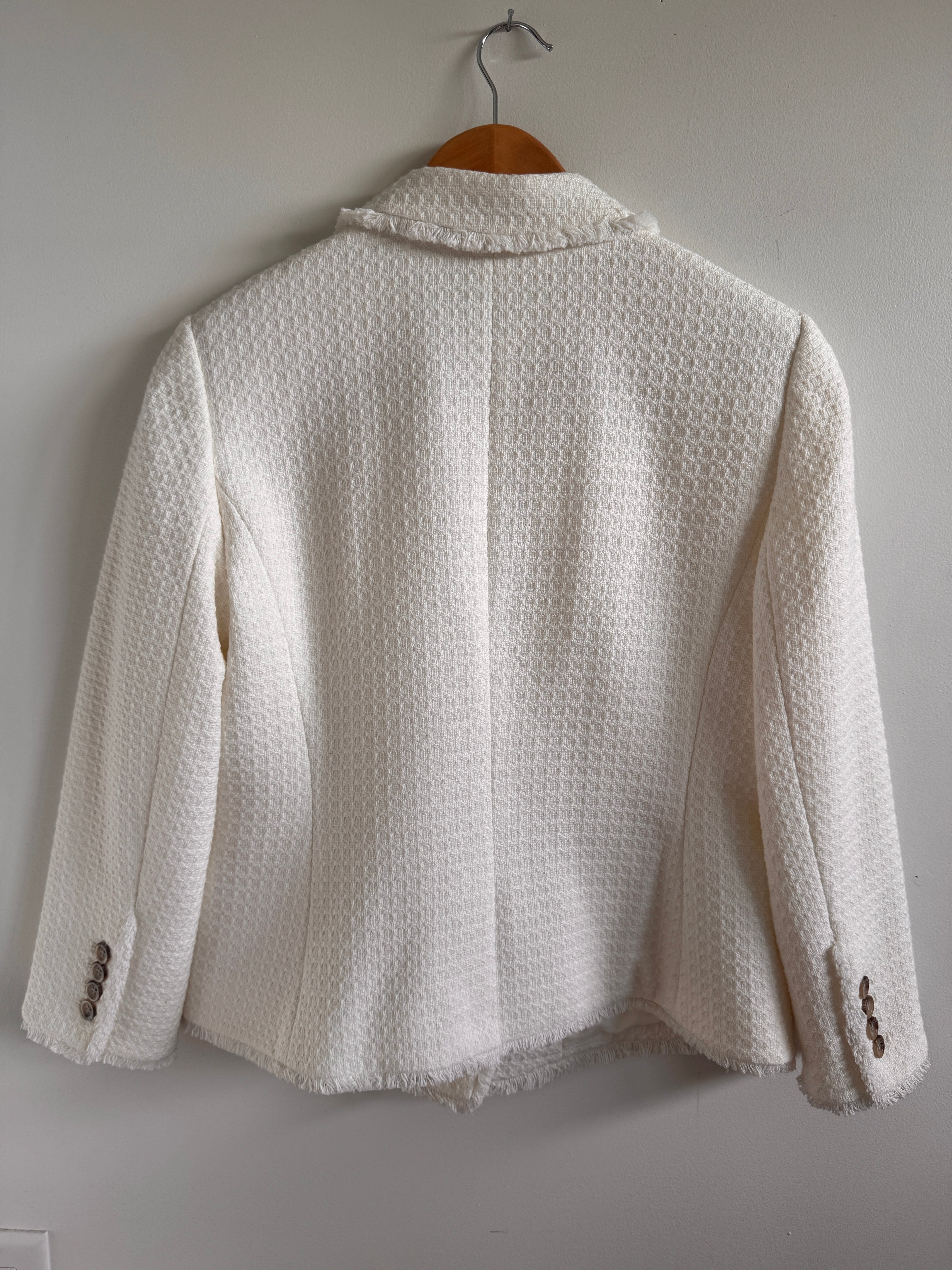 White textured jacket on a hanger against a light gray background