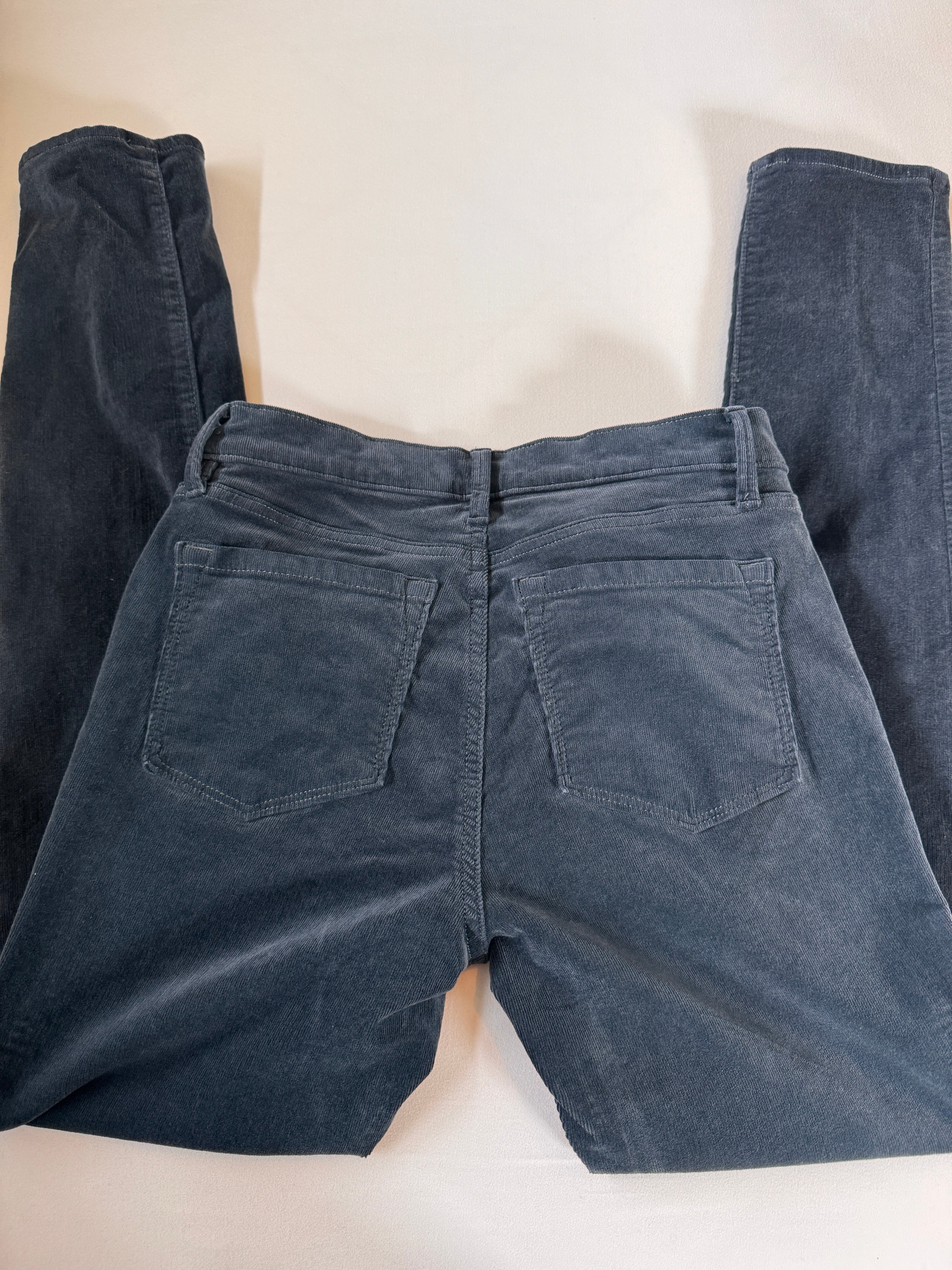 Folded dark blue jeans on a light beige surface