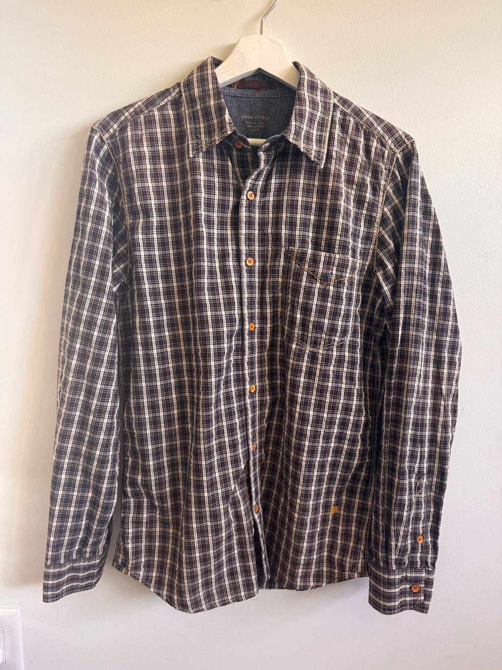 Plaid shirt on a hanger against a white wall