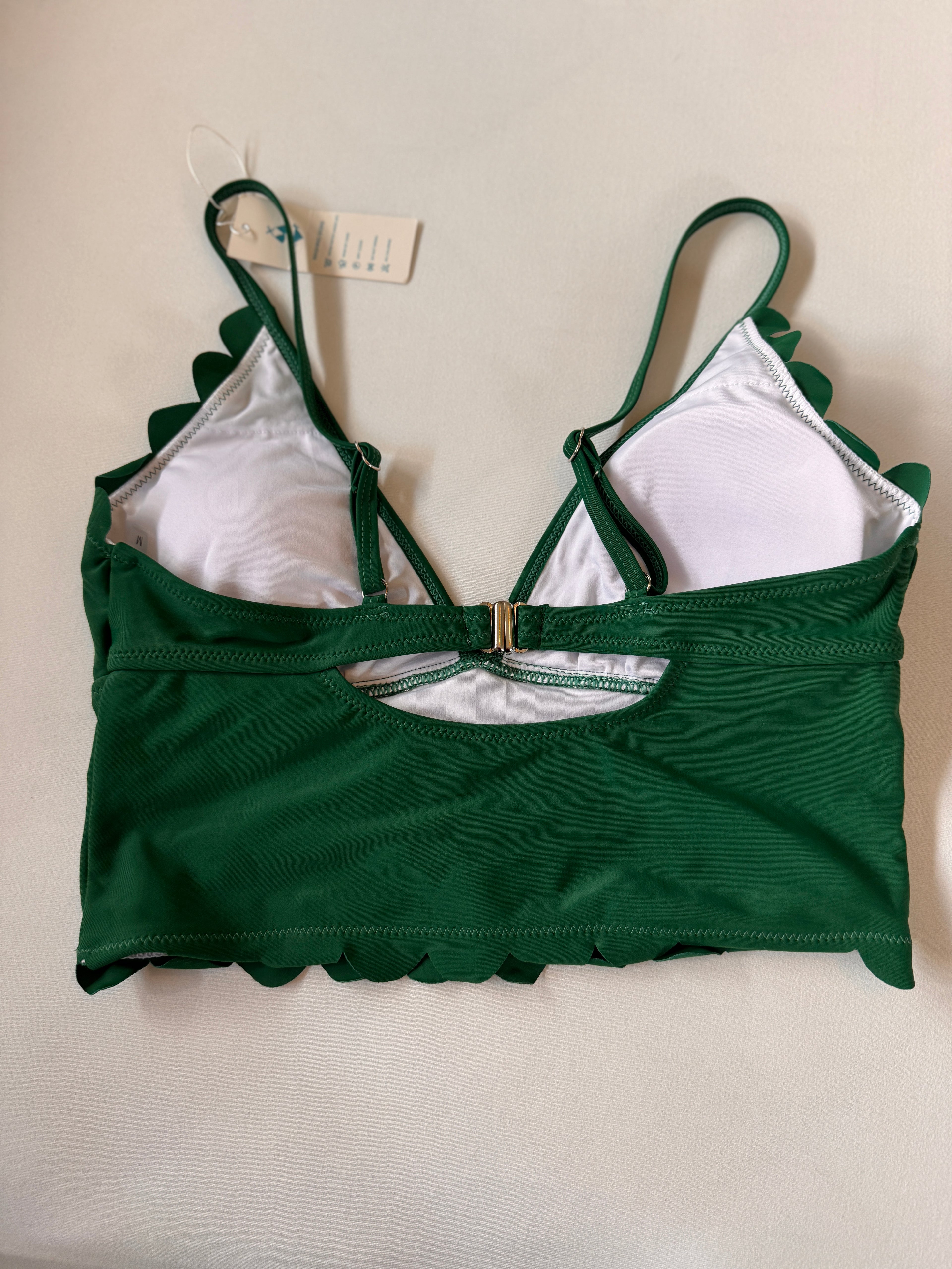 Green bikini top with scalloped edges on a white background
