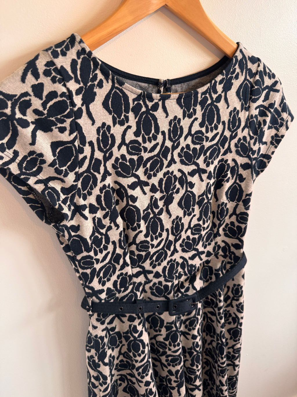 Black floral patterned fabric on a wooden hanger against a white background