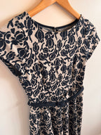Black floral patterned fabric on a wooden hanger against a white background