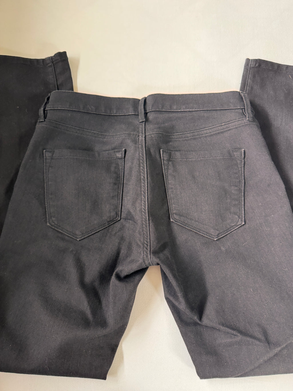 Dark gray pants with two front pockets on a light beige background