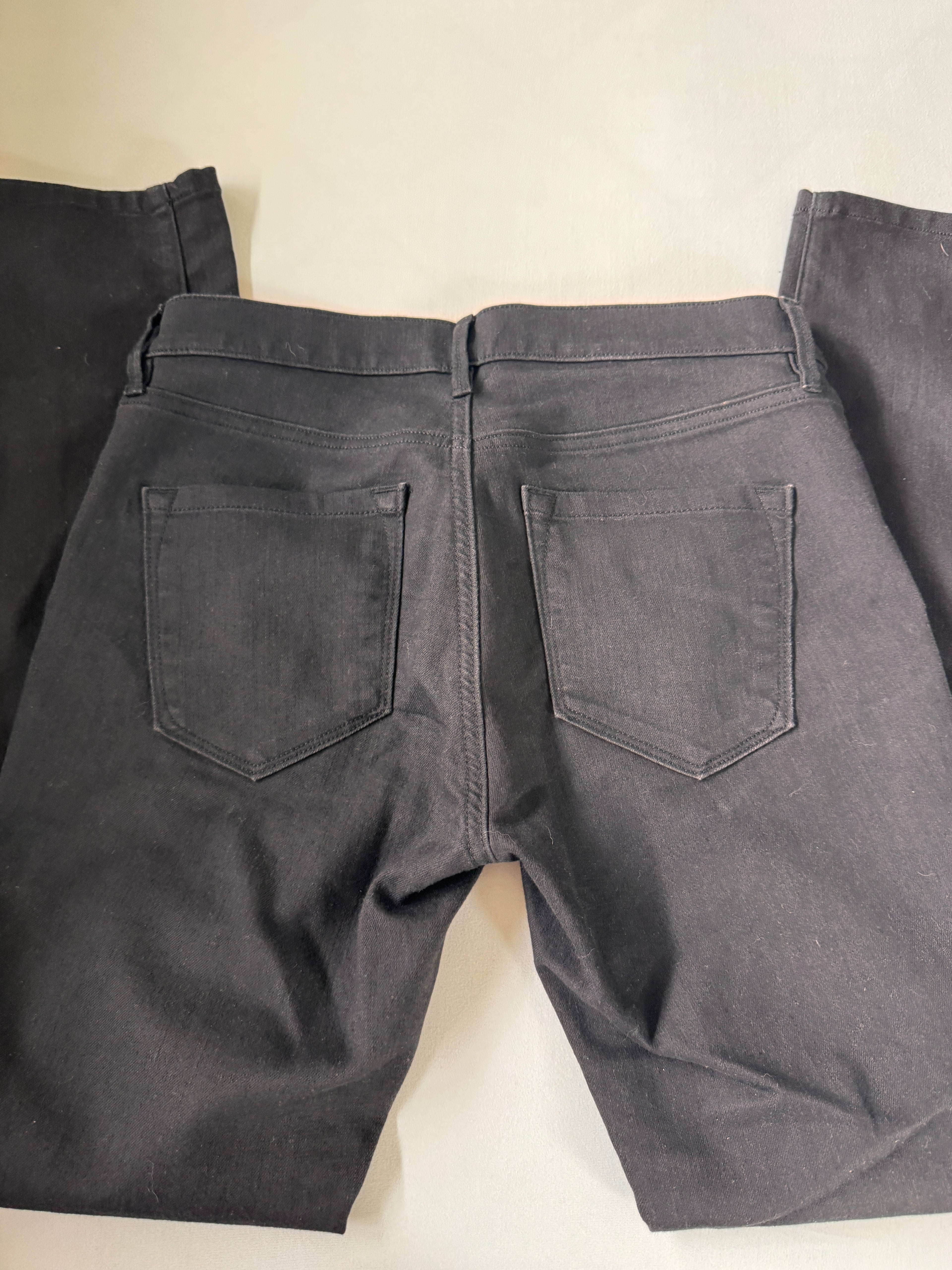 Dark gray pants with two front pockets on a light beige background