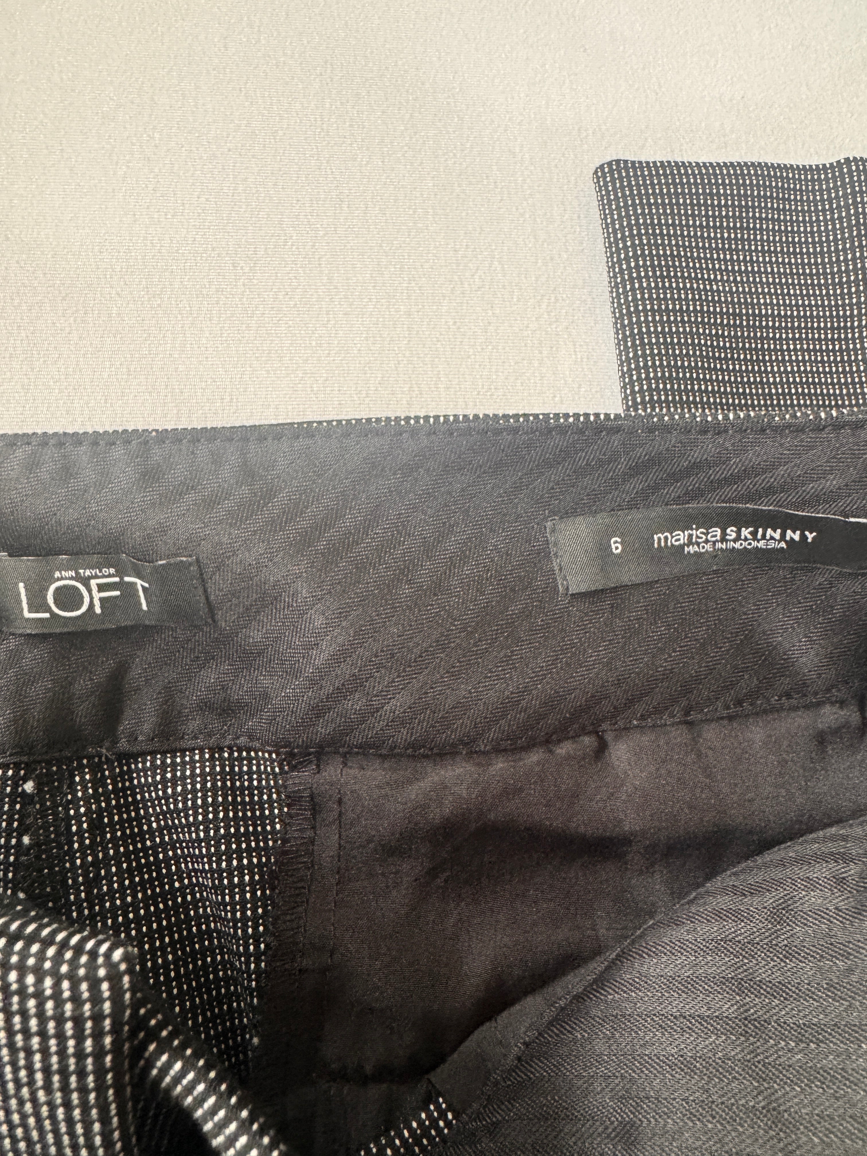 Close-up of a gray jacket with 'LOFT' and 'Marisa Skinny' labels on a beige background