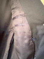 Close-up detail of a navy-colored suit jacket, showing the interior lining, a button closure, and a welt pocket.