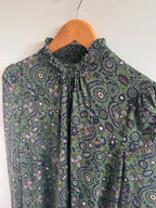 Green floral-patterned fabric on a wooden hanger against a white background