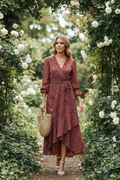 Lifestyle image of woman in floral wrap dress with purse walking in garden