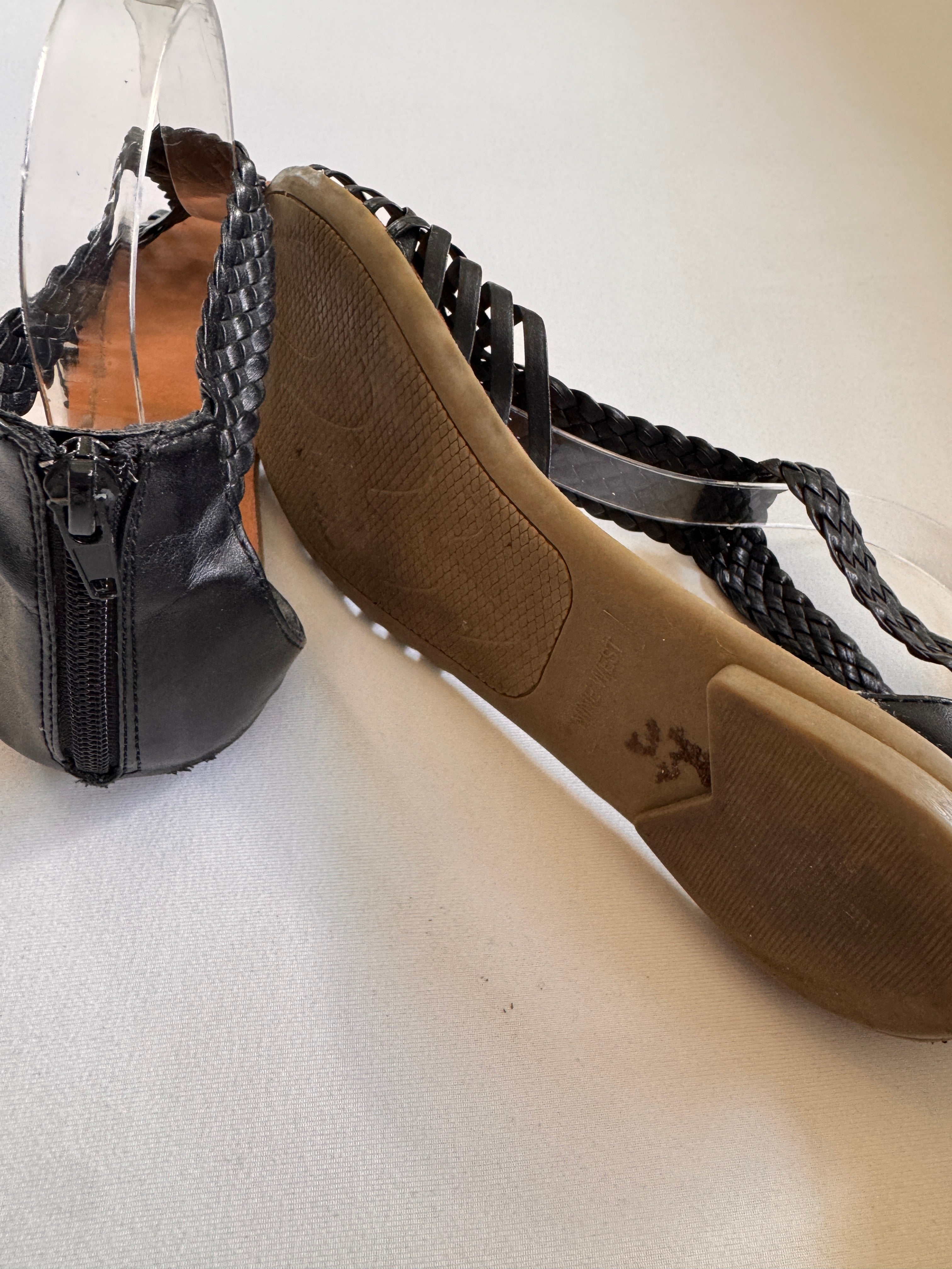 Soles of a black leather sandals showing wear of the shoes