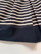 Close-up of a black and white striped fabric with a solid black border on a light background