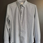 Gray patterned shirt on a hanger against a dark background