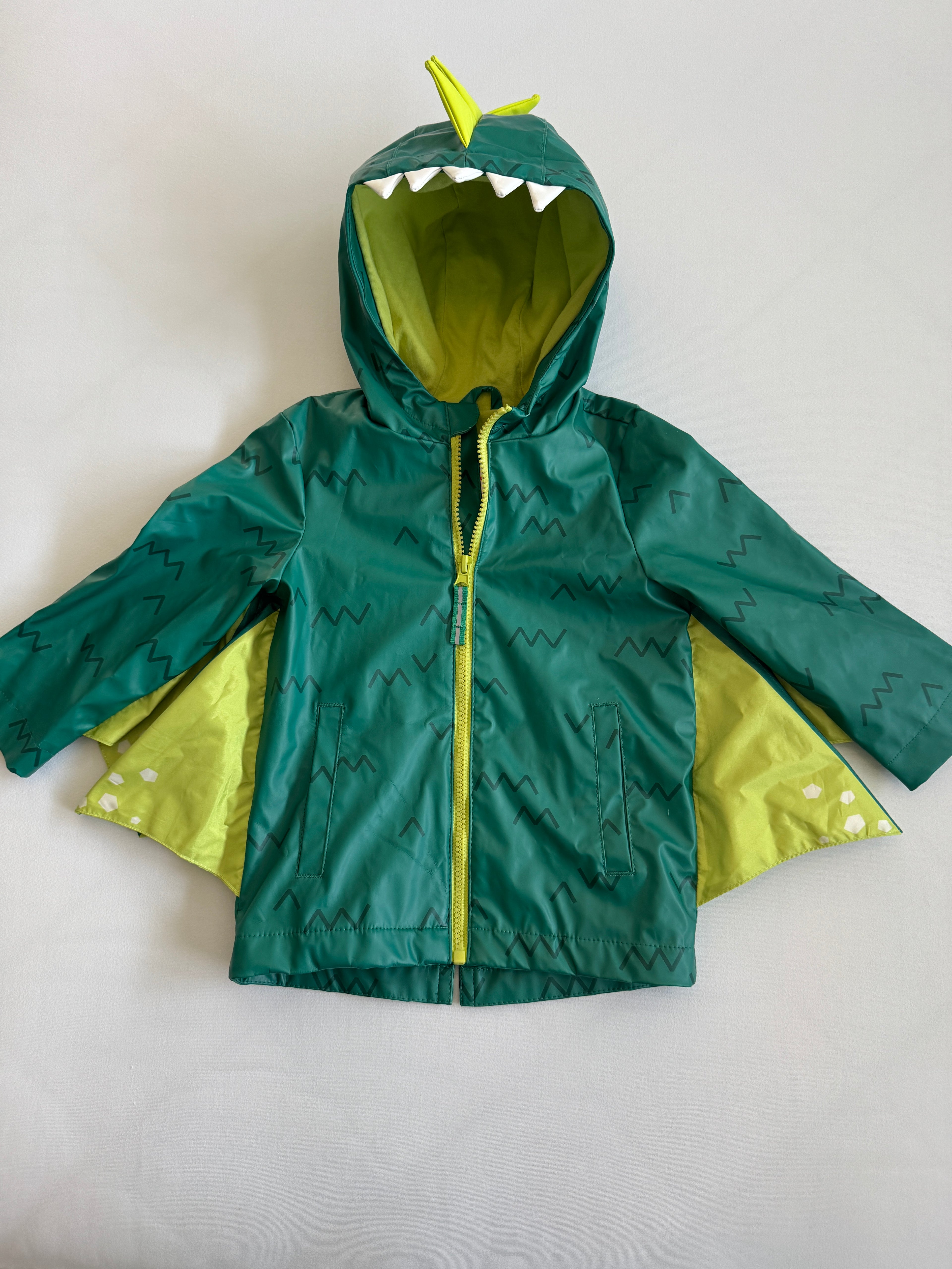 Green children's raincoat with dinosaur design on a white background