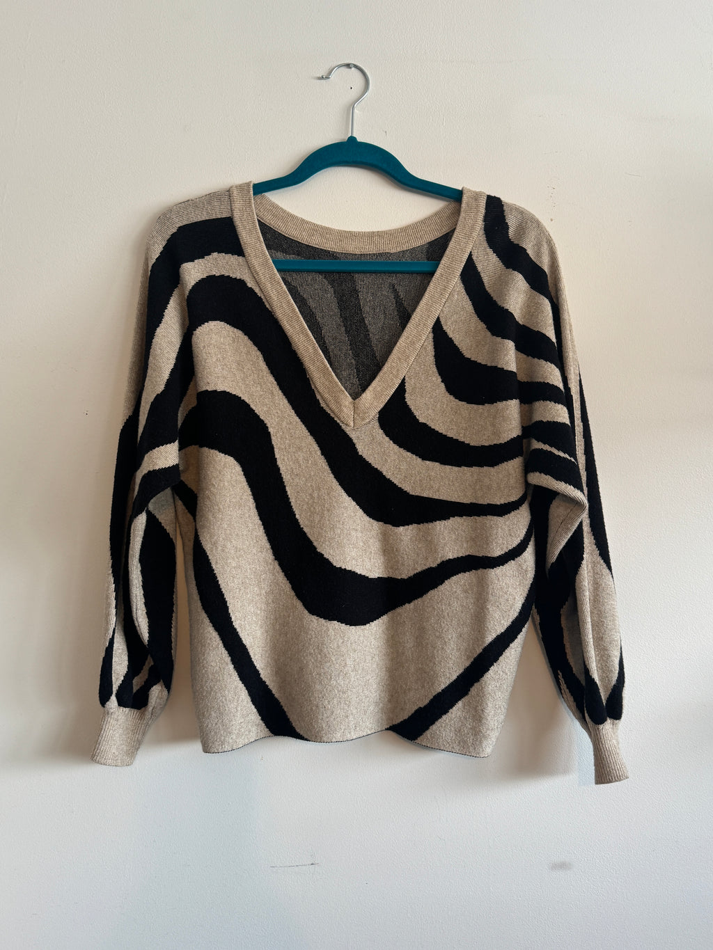 Zebra-striped sweater on a hanger against a white background