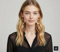 Woman wearing gold hoop earrings with a plain background