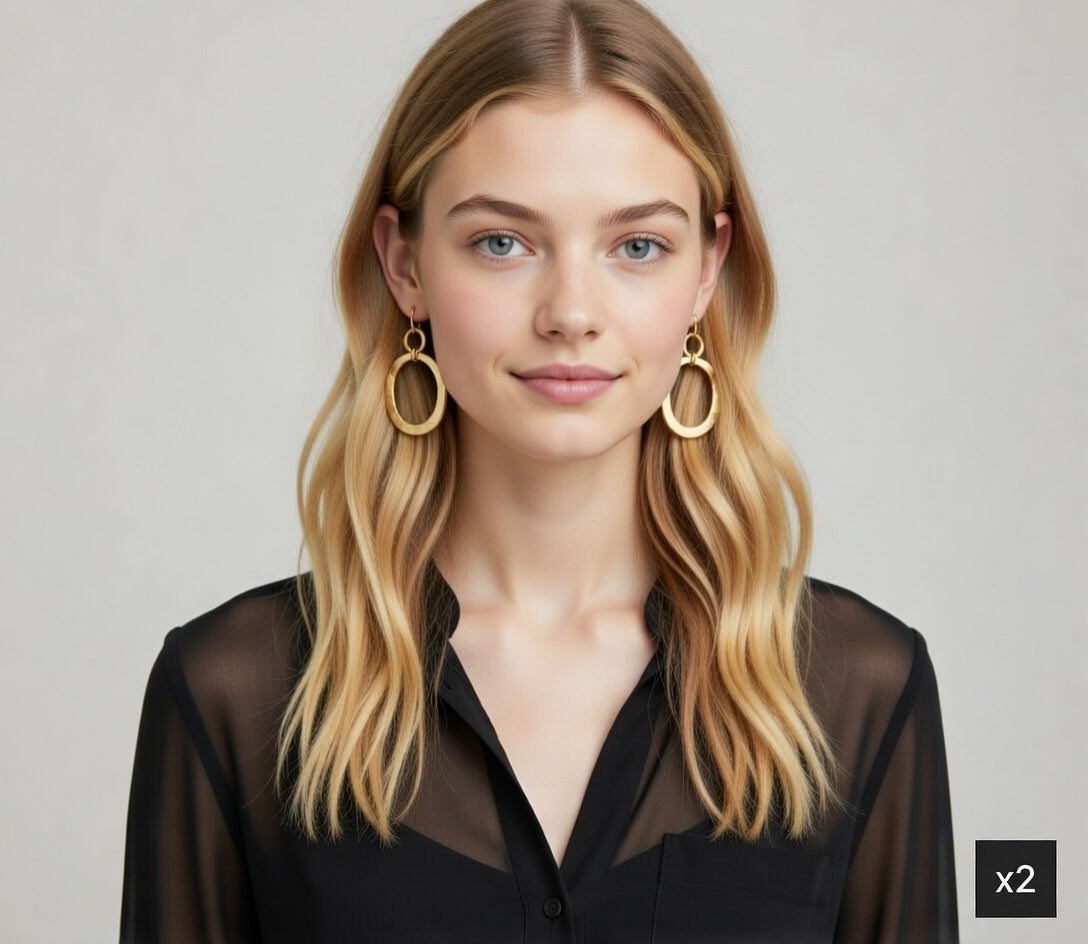 Woman wearing gold hoop earrings with a plain background