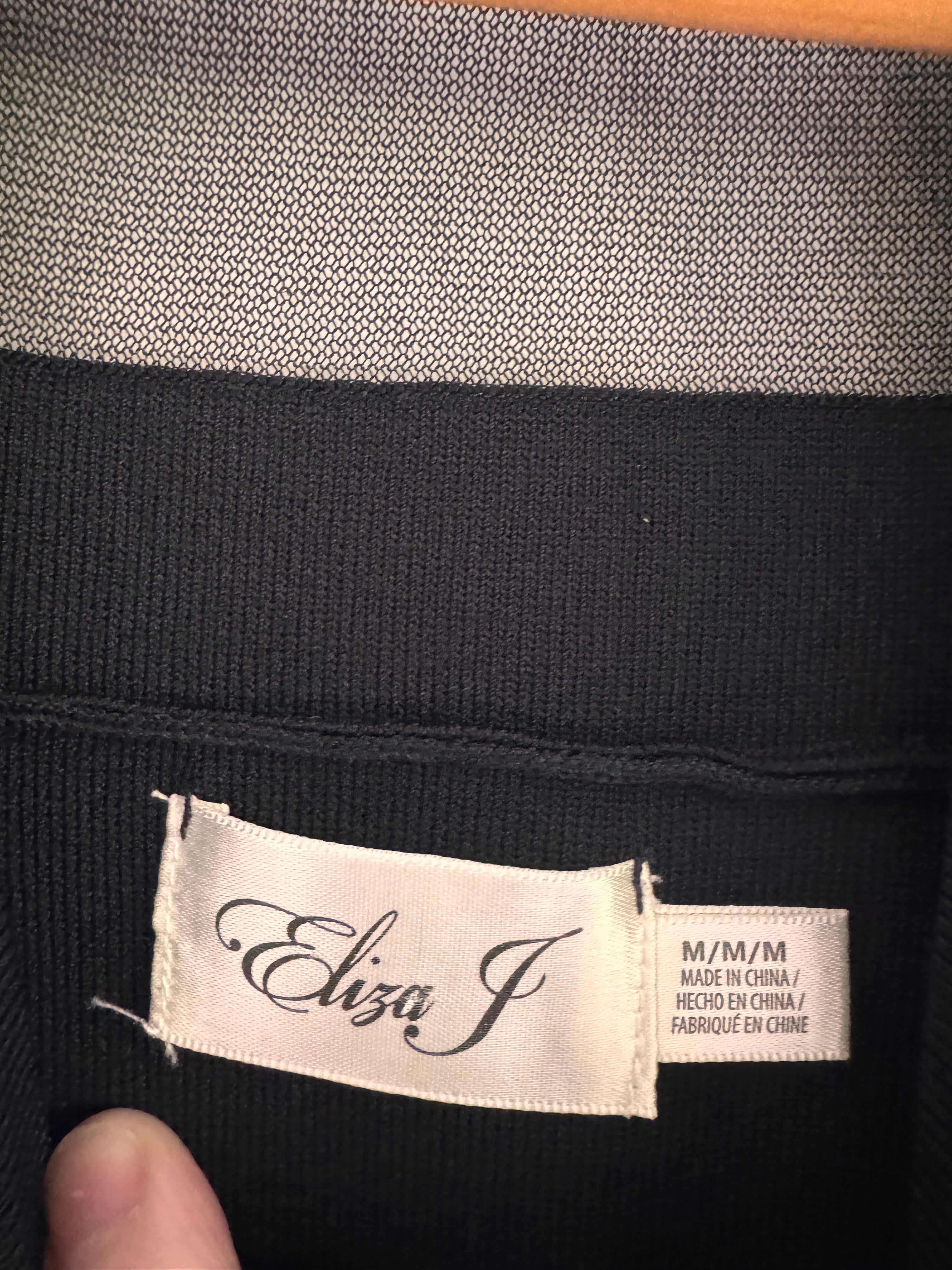 Close-up of a black garment with a visible brand label.
