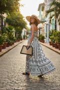 Woman in strapless white geometric dress with rattan hat carrying bag