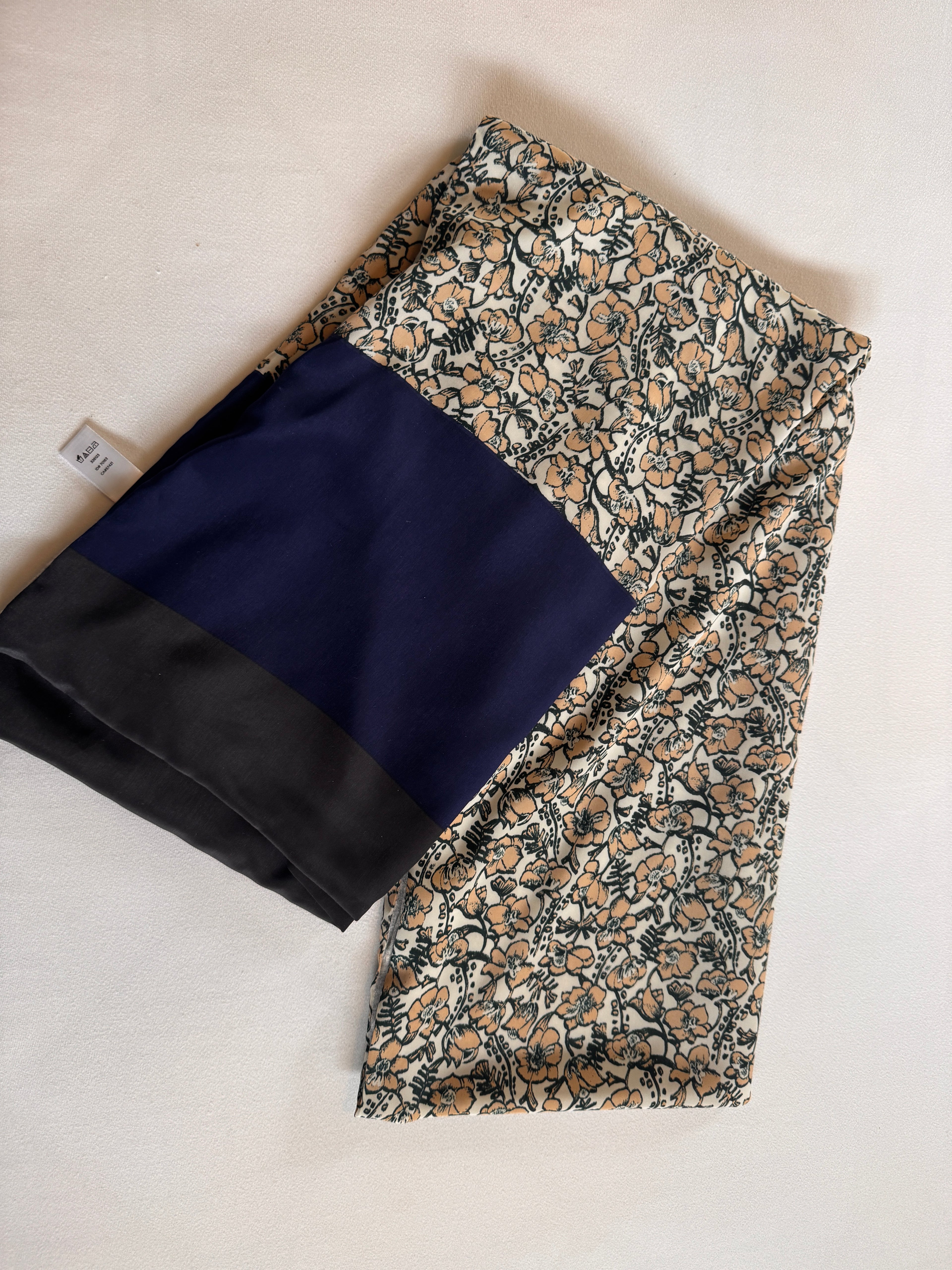 Two folded fabrics, one with a floral pattern and the other navy blue, on a light beige surface.