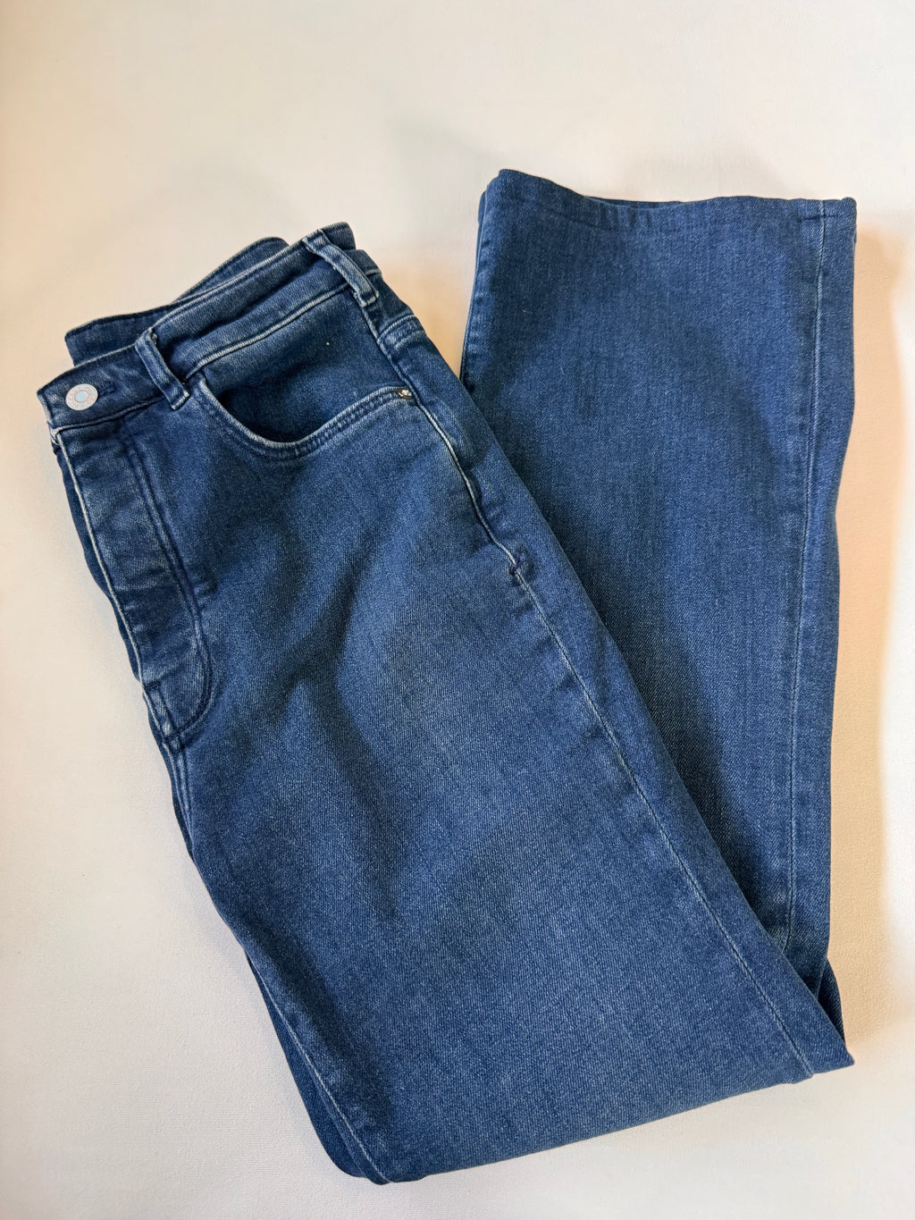 Folded blue jeans on a beige surface