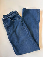 Folded blue jeans on a beige surface