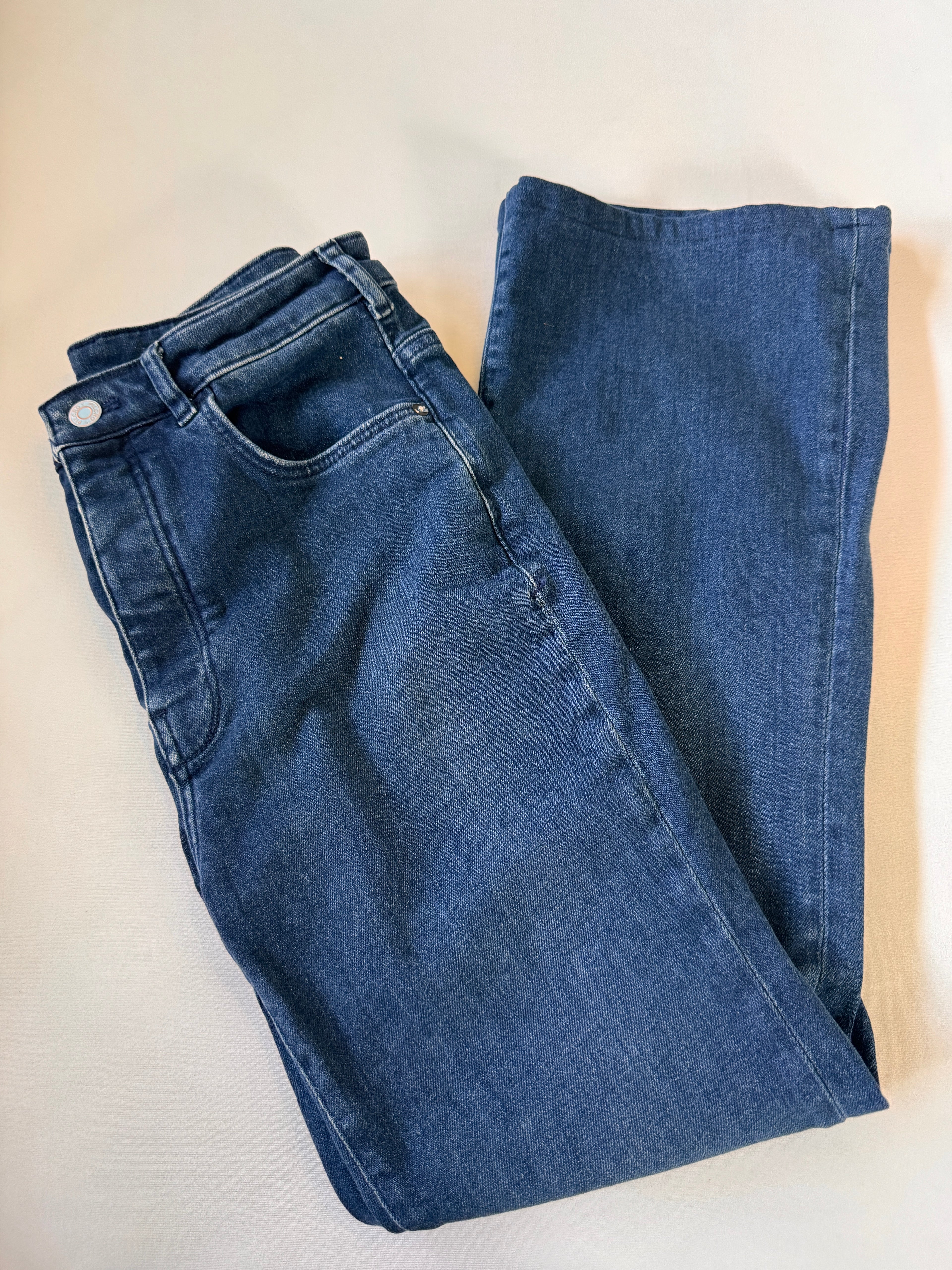 Folded blue jeans on a beige surface