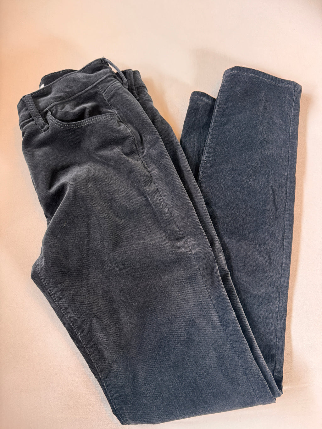 Folded dark blue jeans on a beige surface