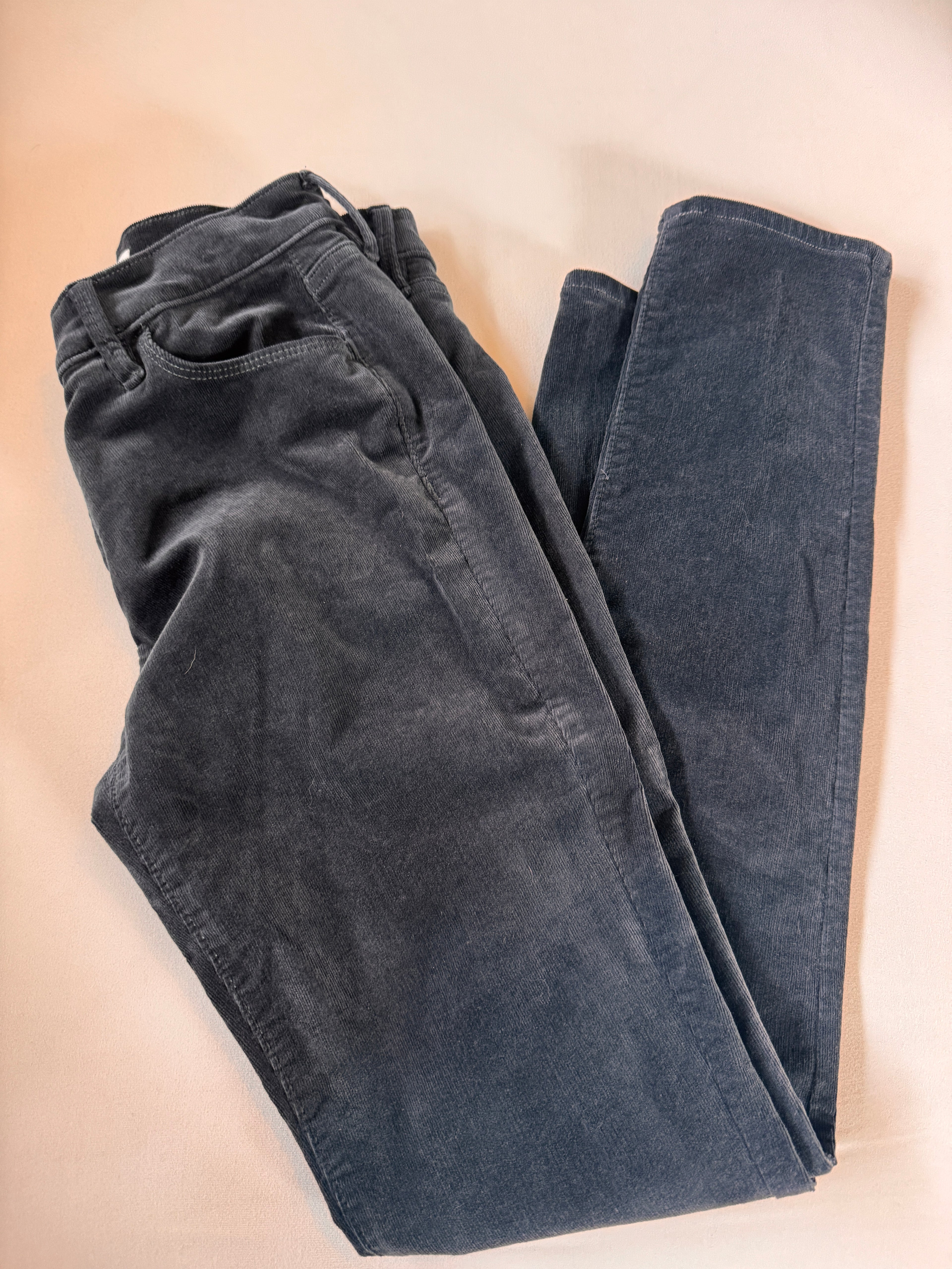 Folded dark blue jeans on a beige surface