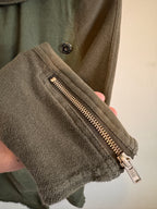 Close-up of a green fleece jacket with a zipper pocket on a plain background