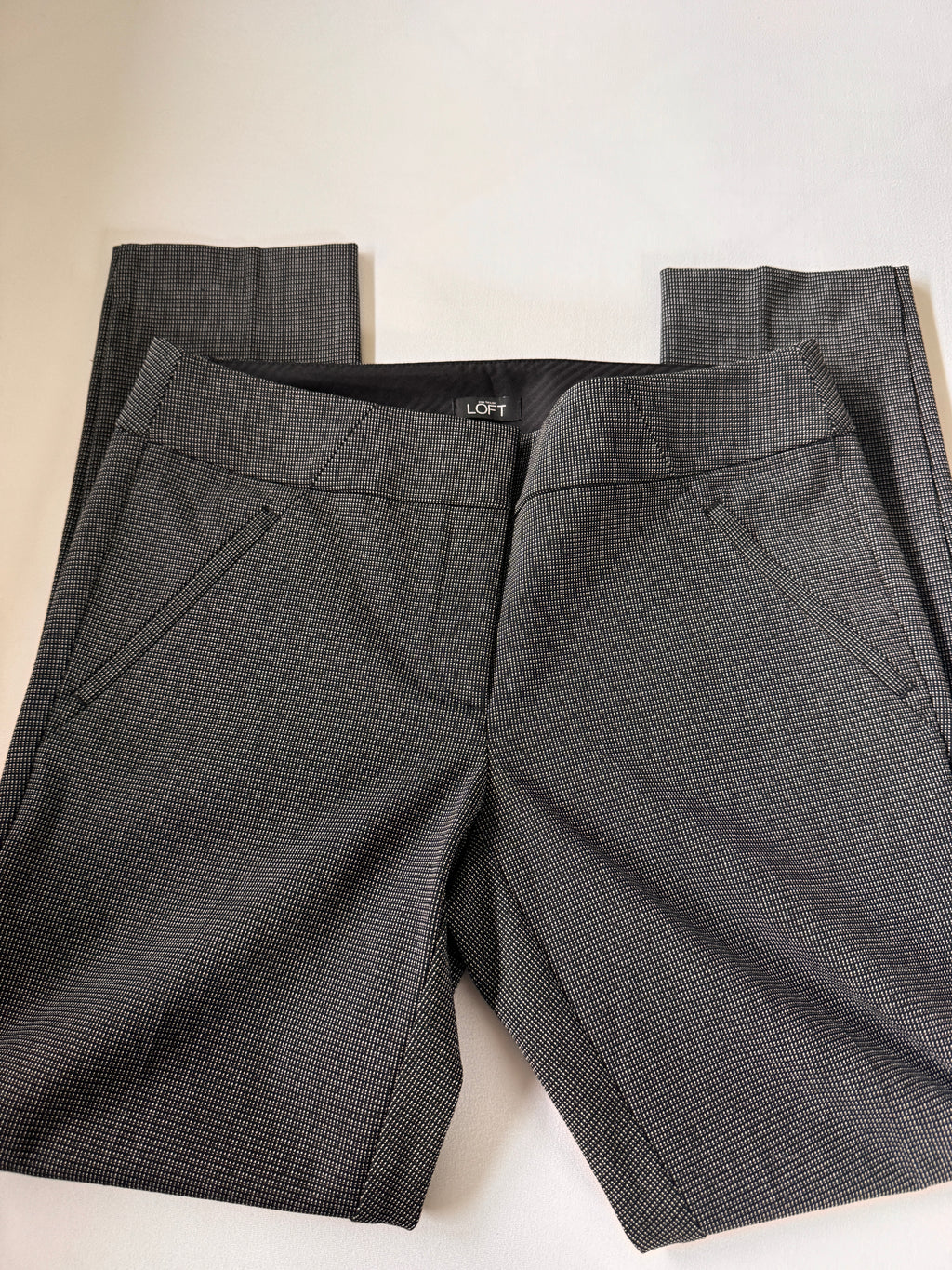Folded dark gray pants on a light beige surface