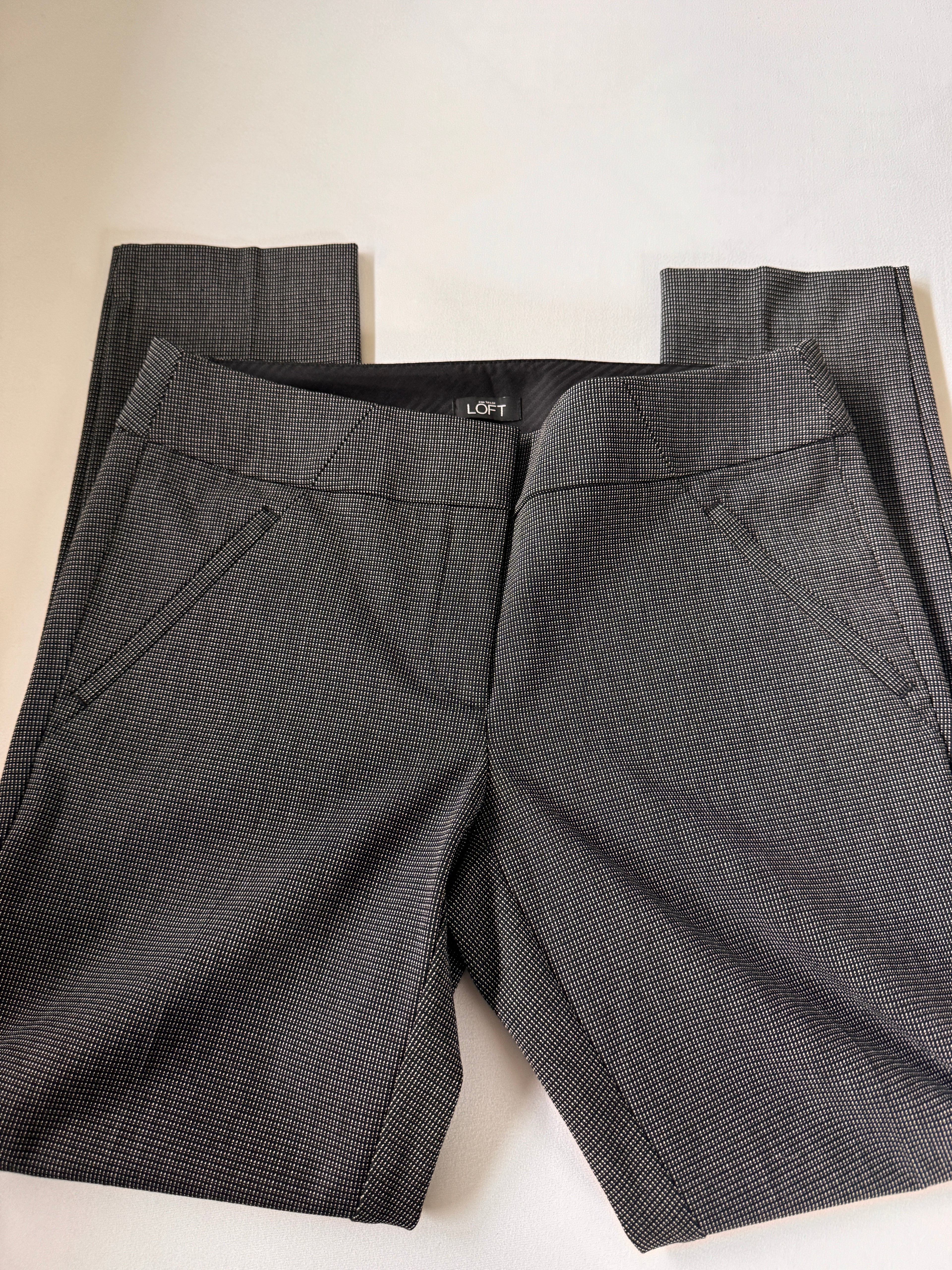 Folded dark gray pants on a light beige surface
