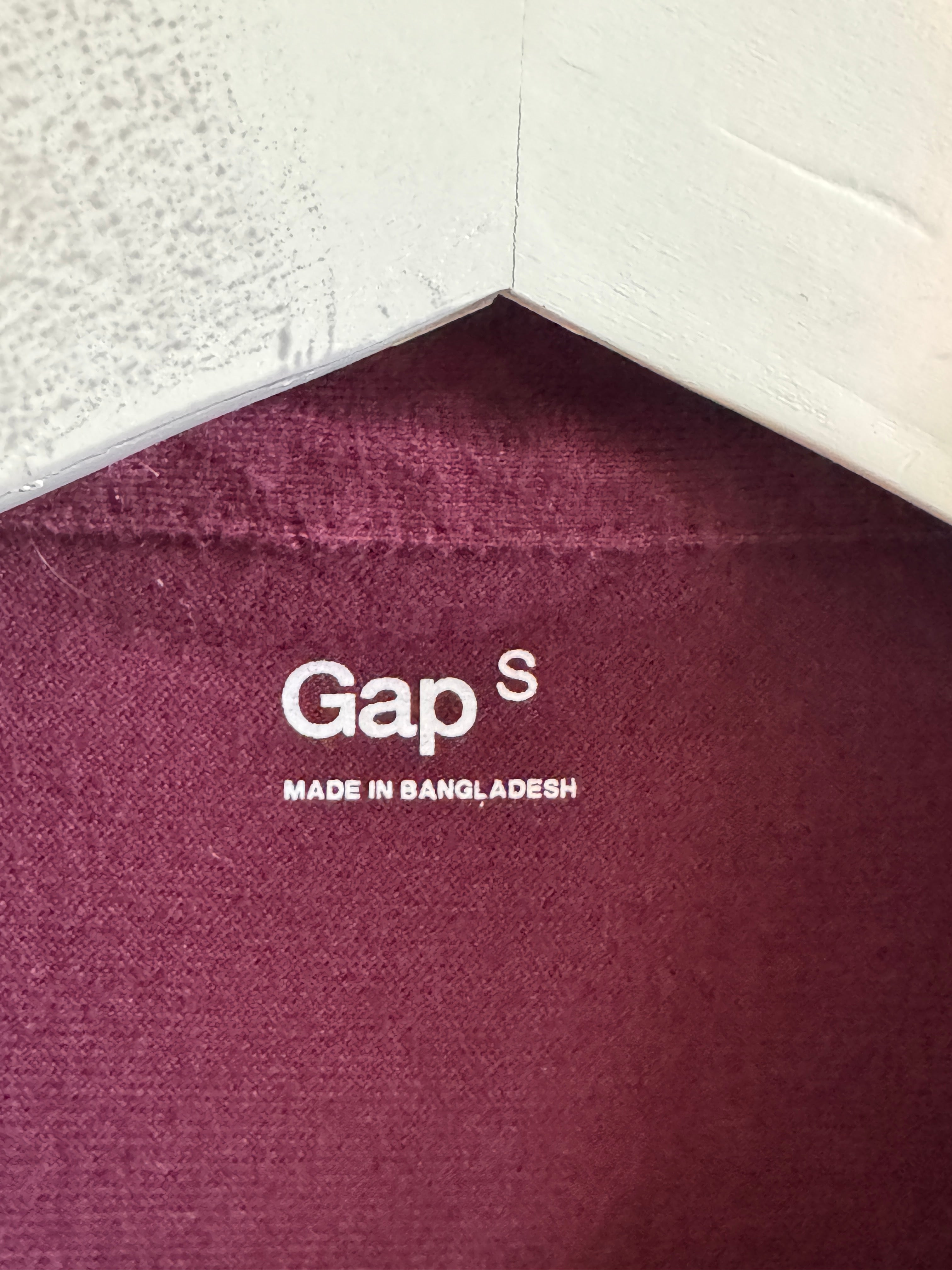 Close-up of a maroon fabric with 'Gap' branding and text.