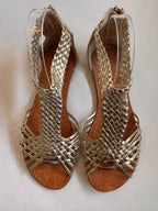 Pair of gold woven sandals on a white background