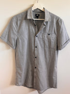 Hanging gray striped shirt on a light beige surface