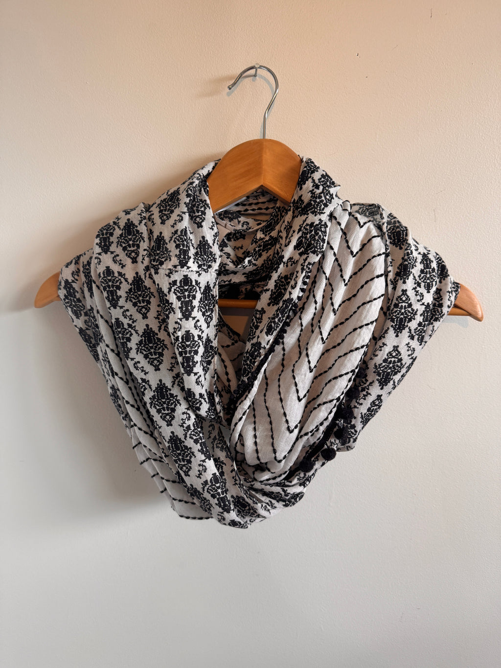 Black and white patterned fabric on a wooden hanger against a beige background