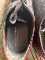 Close-up of a brown leather shoe with visible branding on the sole.
