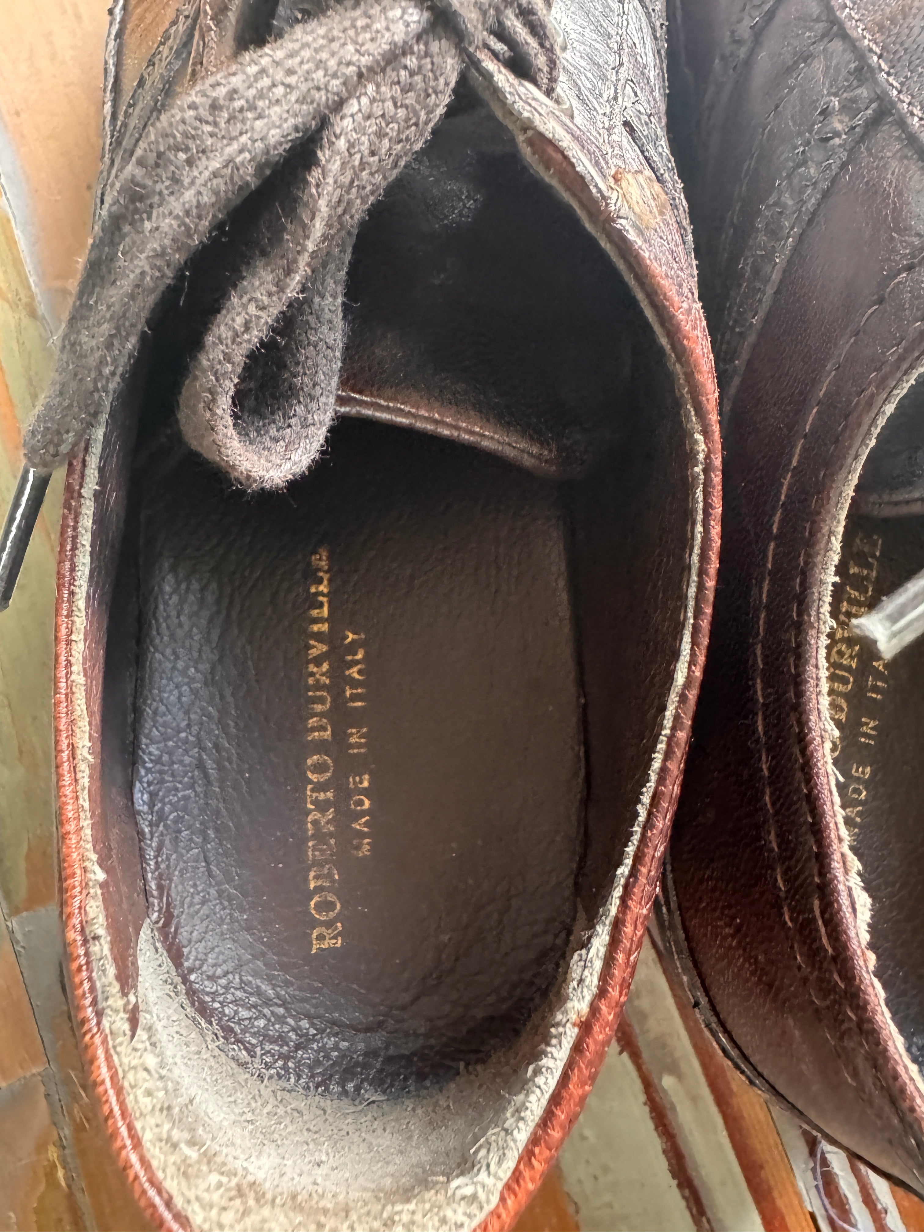 Close-up of a brown leather shoe with visible branding on the sole.
