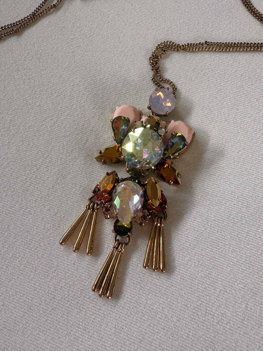Decorative brooch style necklace with gemstones on a light gray background
